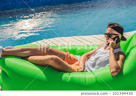 Young man enjoying leisure, lying on the air sofa Lamzac, near the pool Young man enjoying leisure, lying on the air sofa Lamzac, near the pool 101394430