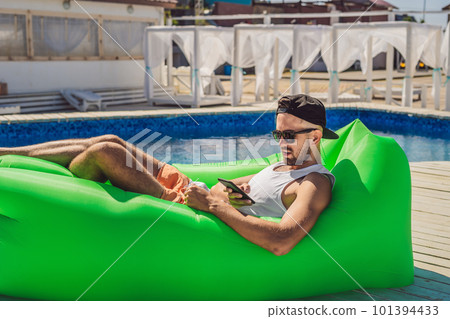 Young man enjoying leisure, lying on the air sofa Lamzac, near the pool Young man enjoying leisure, lying on the air sofa Lamzac, near the pool 101394433