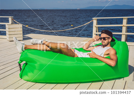 Young man enjoying leisure, lying on the air sofa Lamzac, near the sea Young man enjoying leisure, lying on the air sofa Lamzac, near the sea 101394437