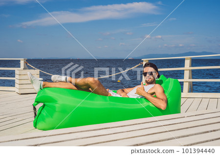 Young man enjoying leisure, lying on the air sofa Lamzac, near the sea Young man enjoying leisure, lying on the air sofa Lamzac, near the sea 101394440