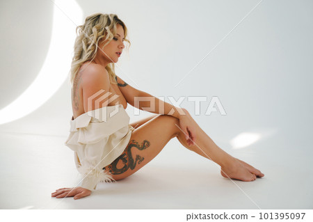 a gentle naked blonde woman in a white shirt on the floor.  101395097