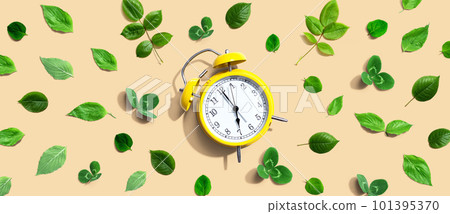 Yellow vintage alarm clock with green leaves 101395370