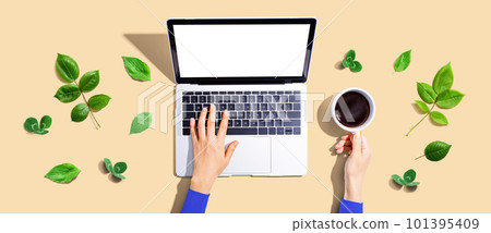 Person using a laptop computer with green leaves 101395409