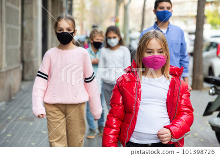 Schoolchildren in masks walking together on street Schoolchildren in masks walking together on street 101398726