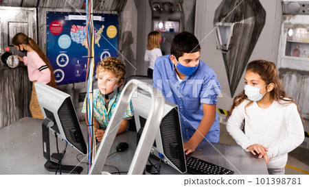 Tweens in protective masks using computer in lost room bunker 101398781