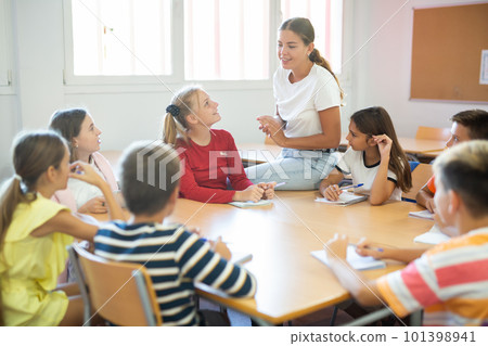 Kids sitting around desk in classroom and studying during lesson Kids sitting around desk in classroom and studying during lesson 101398941