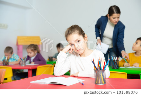 Tired schoolgirl at pupils desk at lesson 101399076