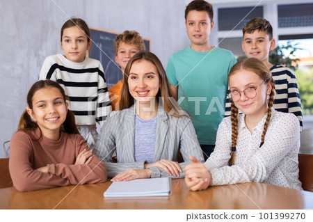 Portrait of happy preteens young learners and their female teacher smiling at camera after lesson in middle school 101399270