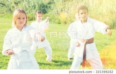 Positive children practicing karate in park 101399282
