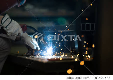 The hand of a factory worker performing arc welding with sparks The hand of a factory worker performing arc welding with sparks 101400528