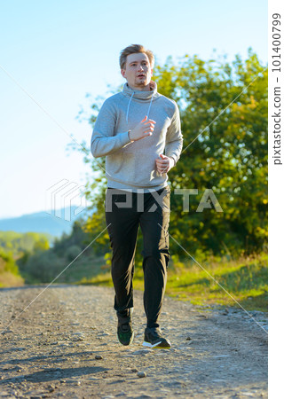 Man jogging in rural nature at beautiful summer day. Sport fitness model caucasian ethnicity training outdoor. 101400799