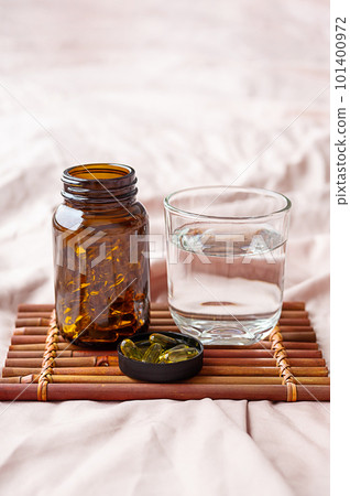 Omega 3 oil capsules and water glass on tray. Fatty acids nutritional supplement for support health. 101400972