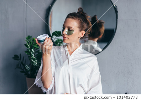 Woman reads the recommendations on using patches for the skin under her eyes Woman reads the recommendations on using patches for the skin under her eyes 101402778