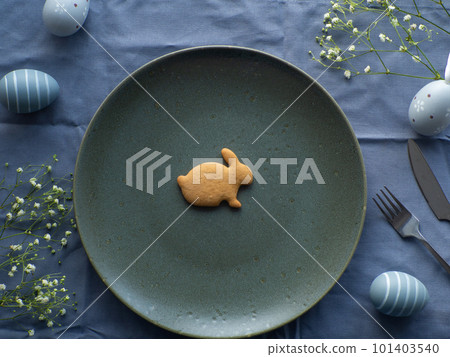 Festive Easter table setting with cookie and flowers on blue background Festive Easter table setting with cookie and flowers on blue background 101403540