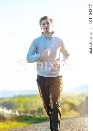 Man jogging in rural nature at beautiful summer day. Sport fitness model caucasian ethnicity training outdoor. 101404207