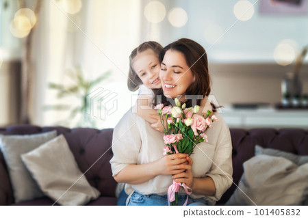 Daughter giving mother bouquet of flowers. 101405832