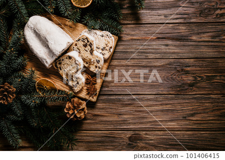 Christmas stollen on wooden background. Traditional christmas german dessert cut into pieces. Cake with nuts, raisins with marzipan and dried fruit on cutting board. baking for xmas 101406415