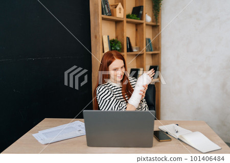 Front view of young woman with broken hand wrapped in white gypsum bandage having online video call, smiling looking to screen, working remotely on laptop computer sitting at desk in home office room Front view of young woman with broken hand wrapped in white gypsum bandage having online video call, smiling looking to screen, working remotely on laptop computer sitting at desk in home office room 101406484