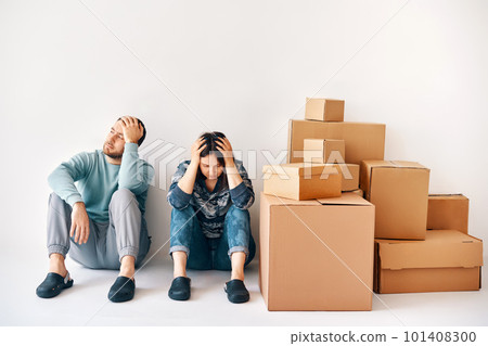 Young couple fell asleep after a moving day sitting on the floor surrounded by cardboard boxes Young couple fell asleep after a moving day sitting on the floor surrounded by cardboard boxes 101408300