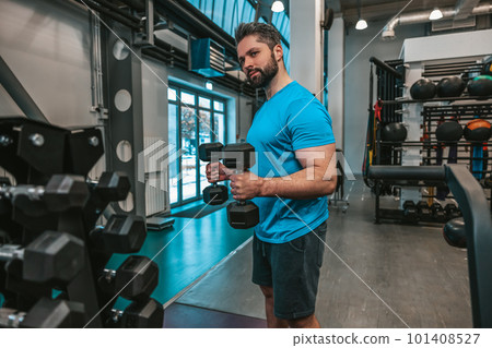 Man working with dumbbells in a sports club 101408527