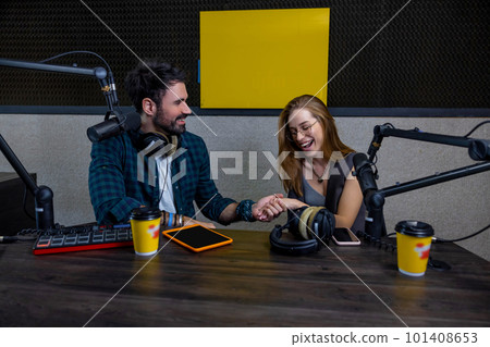 Radio dj talking to a studio guest and looking contented 101408653