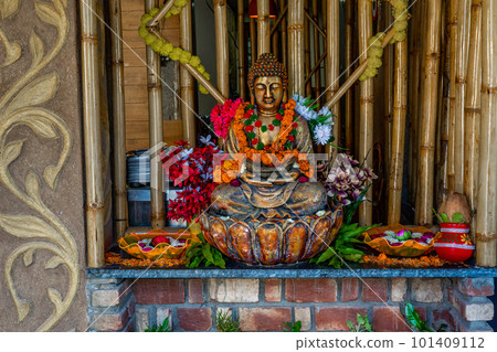Bronze buddha statue sitting in meditation with flower decorations for festival ceremony. Bronze buddha statue sitting in meditation with flower decorations for festival ceremony. 101409112