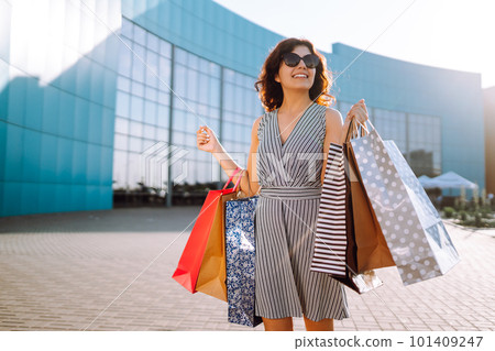 Shopping time. Young woman with shopping bags near the mall. Consumerism, sale, purchases. Shopping time. Young woman with shopping bags near the mall. Consumerism, sale, purchases. 101409247