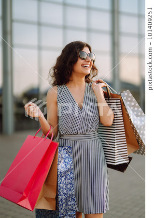 Shopping time. Young woman with shopping bags near the mall. Consumerism, sale, purchases. 101409251