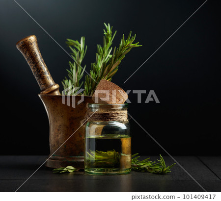 Bottle of rosemary aromatherapy oil extract with fresh rosemary branches. 101409417
