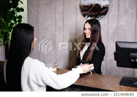 Woman touching credit card to card reader terminal to pay for hotel services Woman touching credit card to card reader terminal to pay for hotel services 101409640