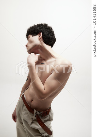 Portrait of young handsome man with fit relief body, posing shirtless in beige pants against white studio background 101411688