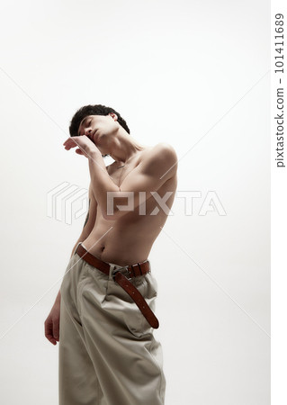Self-care. Portrait of young handsome man with fit body, posing shirtless in beige pants against white studio background Self-care. Portrait of young handsome man with fit body, posing shirtless in beige pants against white studio background 101411689