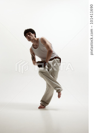Portrait of young stylish man in pastel colored clothes, posing in singlet and classical pants against white studio background. Portrait of young stylish man in pastel colored clothes, posing in singlet and classical pants against white studio background. 101411690
