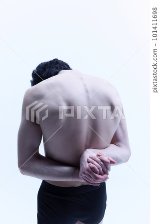 Round back, healthy spine. Young guy posing shirtless, holding hands behind back against white studio background. Relief male body 101411698