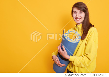 Image of fitness woman ready for workout, standing and holding blue yoga mat isolated over white background. Sporty fit and fresh smiling Caucasian female before workout, copy space for advertisment. 101412318