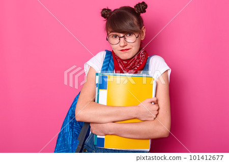Charming student shrugs shoulders, she does not know answer friend question about new timetable. Beautiful schoolgirl holds paper folders and bag isolated over pink background. Education concept. 101412677