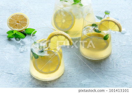 Lemonade with mint. Lemon water drink with ice. Two glasses and a pitcher Lemonade with mint. Lemon water drink with ice. Two glasses and a pitcher 101413101