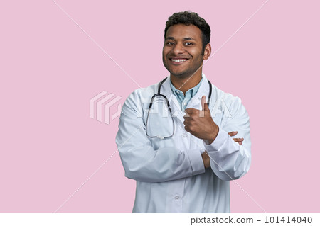 Portrait of indian male doctor with stethoscope in showing thumb up. Isolated on pink background. 101414040