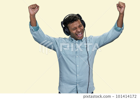 Emotional young Indian man wears blue shirt listen to music in headphones. Isolated on white background. 101414172