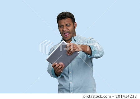 Excited young south asian man playing race game on tablet pc. Isolated on pastel blue background. 101414238