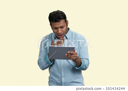 South asian man with expression of bewilderment and surprise holding tablet pc. Puzzled indian guy on white background. 101414244