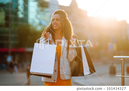 Young woman with shopping bags walking on street. Sale, shopping and happy people concept. 101414327