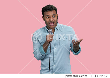 Portrait of a young handsome indian man with microphone. Isolated on pink background. 101414487