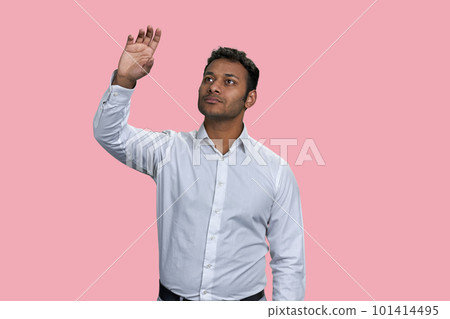 Brown indian businessman touching imaginery virtual screen. Isolated on pink background. Brown indian businessman touching imaginery virtual screen. Isolated on pink background. 101414495