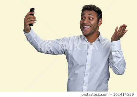 Cheerful indian business man smiling as talking to friend via mobile phone. Waving hand saying hi or hello. Isolated on white background. Cheerful indian business man smiling as talking to friend via mobile phone. Waving hand saying hi or hello. Isolated on white background. 101414539