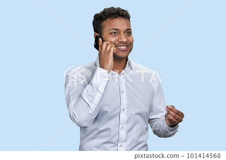 Handsome young indian man talking on the mobile phone. Good talk with friend. Isolated on pale blue background. Handsome young indian man talking on the mobile phone. Good talk with friend. Isolated on pale blue background. 101414568