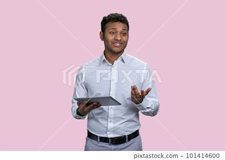 Young southeast asian man giving a speech using tablet pc. Isolated on pink background. Young southeast asian man giving a speech using tablet pc. Isolated on pink background. 101414600