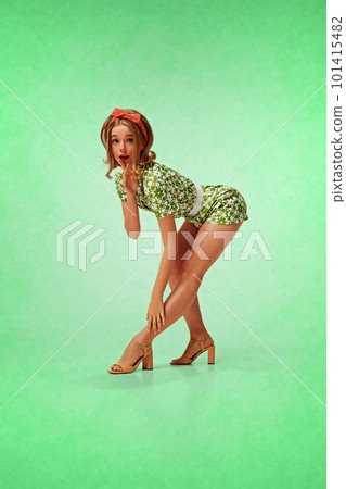 Coquette, blonde, young girl with stylish makeup, attractive dress posing against green background. Flirty, sexy look. Pin-up style Coquette, blonde, young girl with stylish makeup, attractive dress posing against green background. Flirty, sexy look. Pin-up style 101415482
