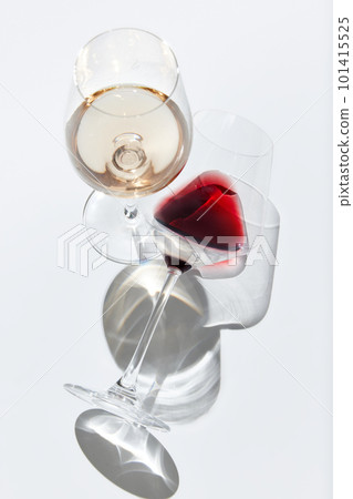 Vertical image of wine glasses filled with red and white wine against white background with reflected lights Vertical image of wine glasses filled with red and white wine against white background with reflected lights 101415525