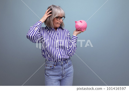 pension savings. a middle-aged woman with gray hair holds a piggy bank with money on a bright studio pension savings. a middle-aged woman with gray hair holds a piggy bank with money on a bright studio 101416597